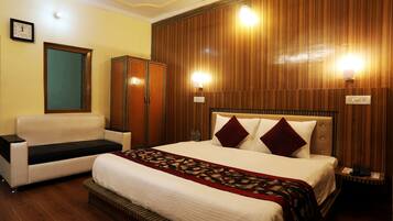 Una habitación de hotel con cama, sofá, armario y dos luces empotradas.