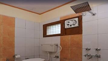 Un baño con inodoro, ventana, ducha y dispensador de papel higiénico.