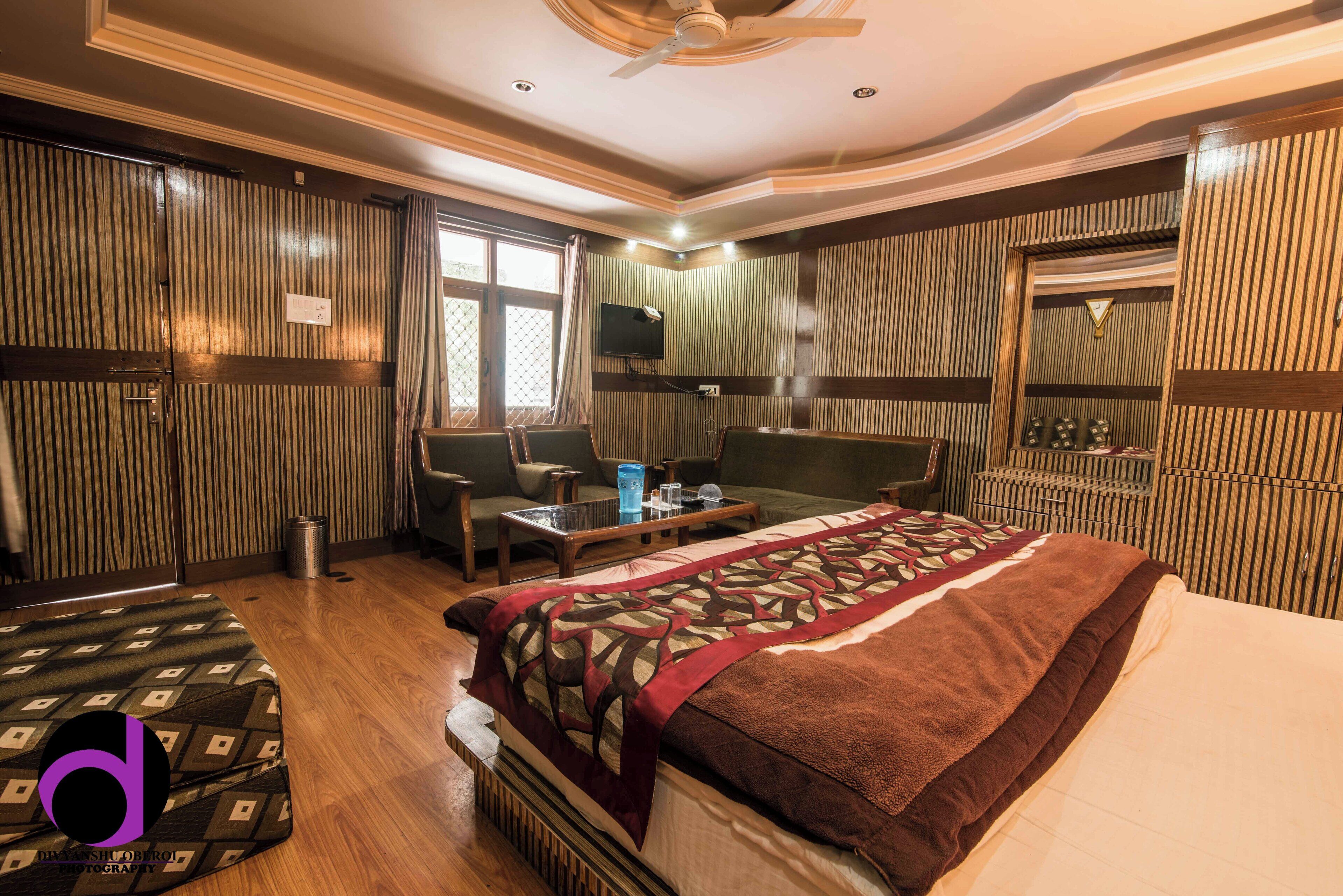 A hotel room with a bed, a desk, a chair, a TV, and a window.