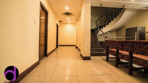 Un pasillo de hotel con un banco, una escalera y una puerta.