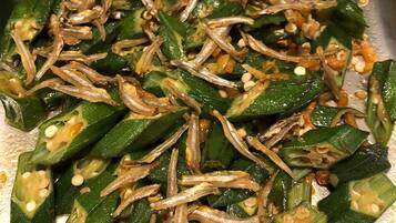 Gros plan sur des bâtonnets de gombo coupés, accompagnés d’oignons et de graines de sésame.