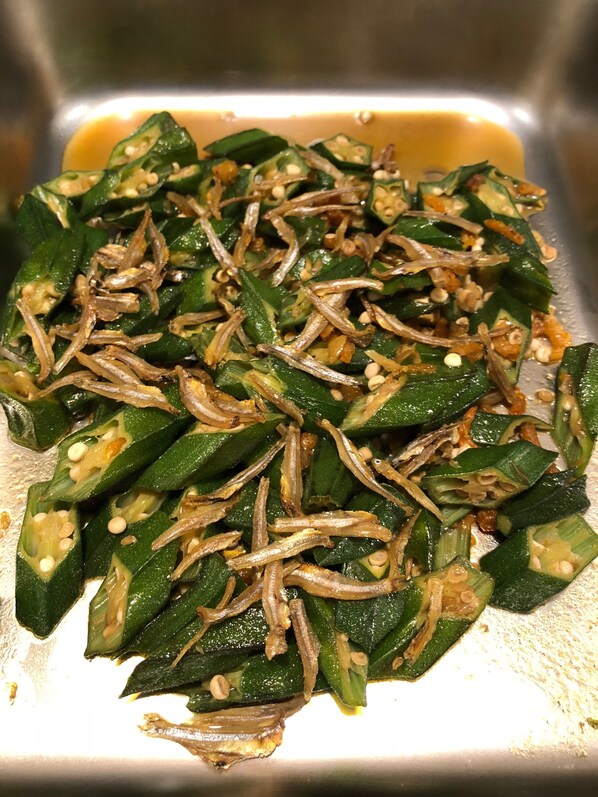 A close-up of sliced okra with onions and sesame seeds.