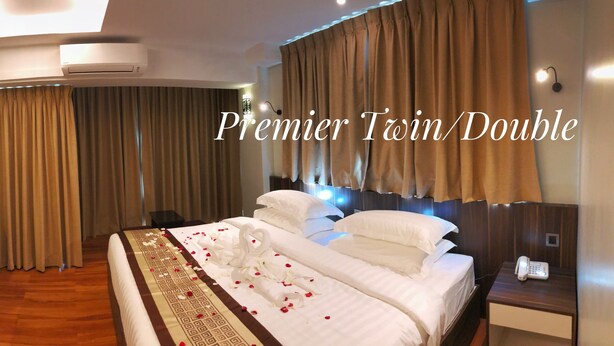A Premier Twin/Double room with a bed, bedside tables, a TV, and a desk with a chair. - Hotel Rose Hill (Yangon)