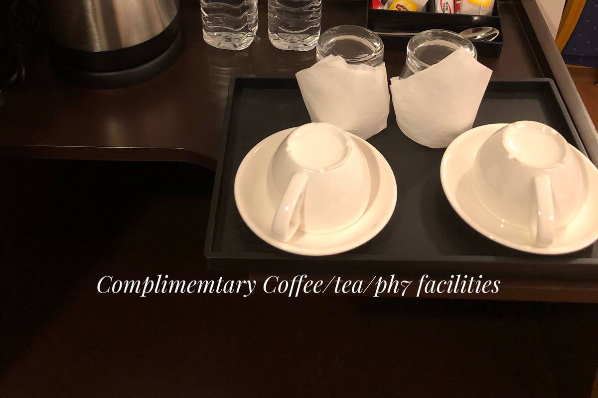A complimentary coffee, tea, and phl facilities setup with a kettle, water bottles, and tea packets on a tray.