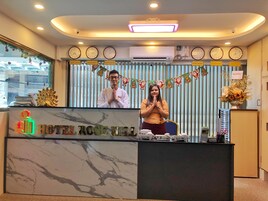 Una recepción de hotel con relojes, un arreglo floral y un letrero que dice 'HOTEL ROSE HILL'.