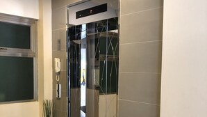 An elevator with a digital display, a potted plant, and a tiled floor. - Hotel Rose Hill (Yangon)