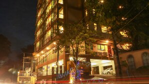 A multi-story hotel with illuminated signage, a visible parking area, and a street with light trails. - Hotel Rose Hill (Yangon)