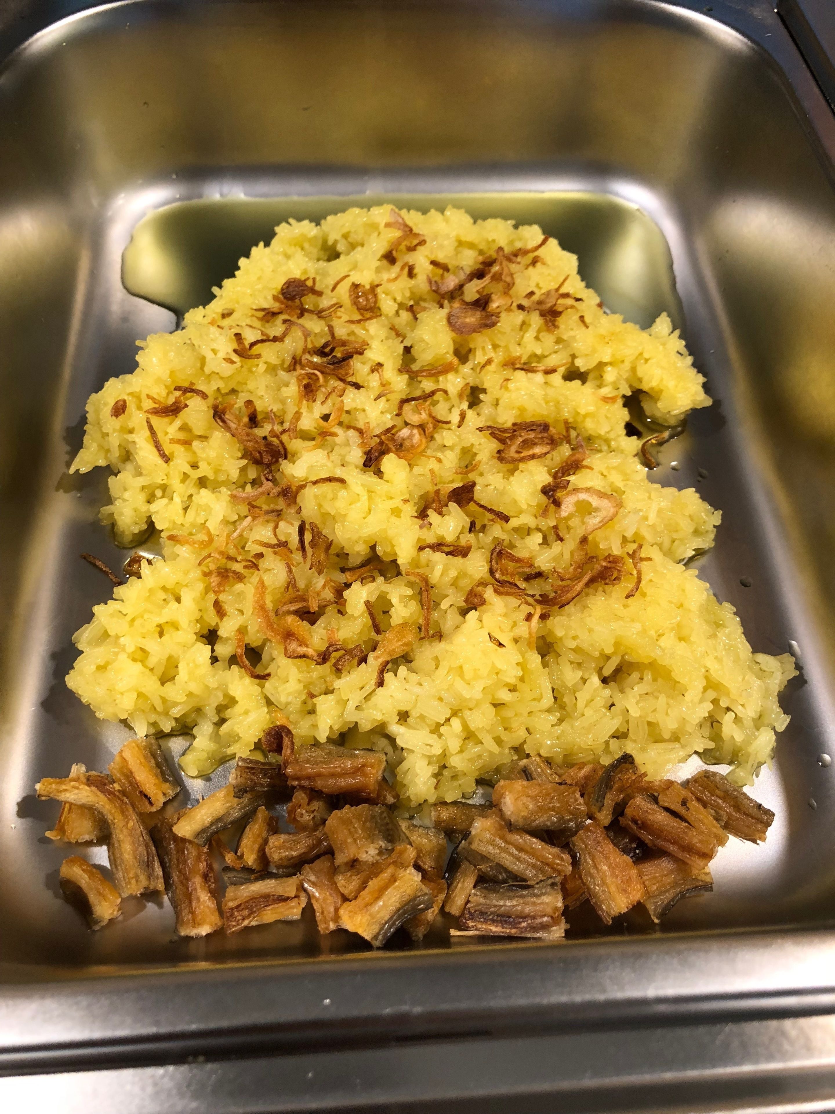 Ein Spülbecken aus Edelstahl mit Reis und gebratenen Zwiebeln auf einem Teller.