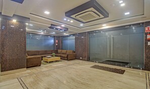 A lobby with a sofa, a coffee table, and a glass elevator. - Treebo Sreema Saltlake Near City Centre Mall (Bidhannagar)