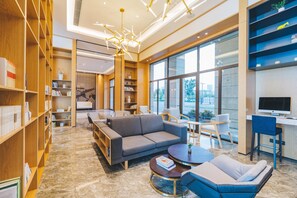 A modern library with a large sofa, a round coffee table, and a desk with a computer. - Atour Hotel Xiang cheng Suzhou (Suzhou)