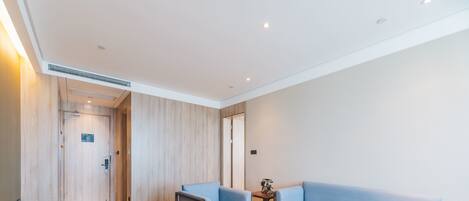 Une chambre d’hôtel moderne avec un plancher en bois, un canapé bleu clair, une petite table ronde et un banc en bois.