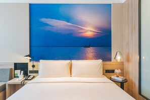 A hotel room with a large bed, a nightstand with a lamp, a phone, and a small table with a vase of flowers. - Atour Hotel Xiang cheng Suzhou (Suzhou)