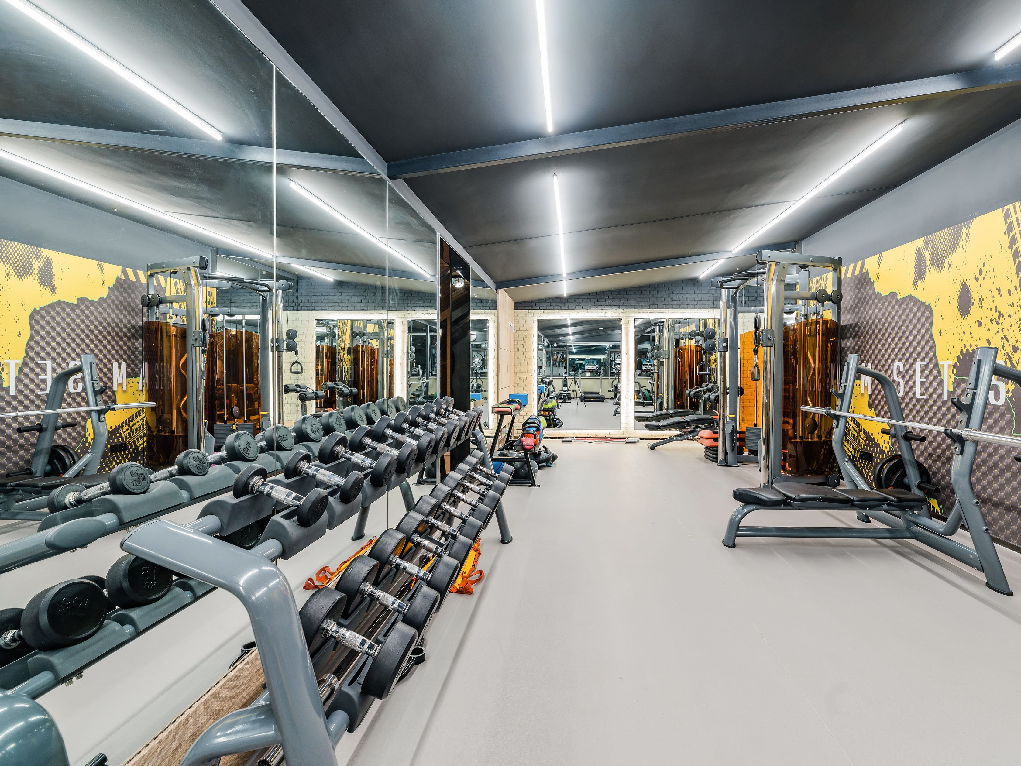 A gym with mirrored walls, weightlifting equipment, and a clean, modern design.