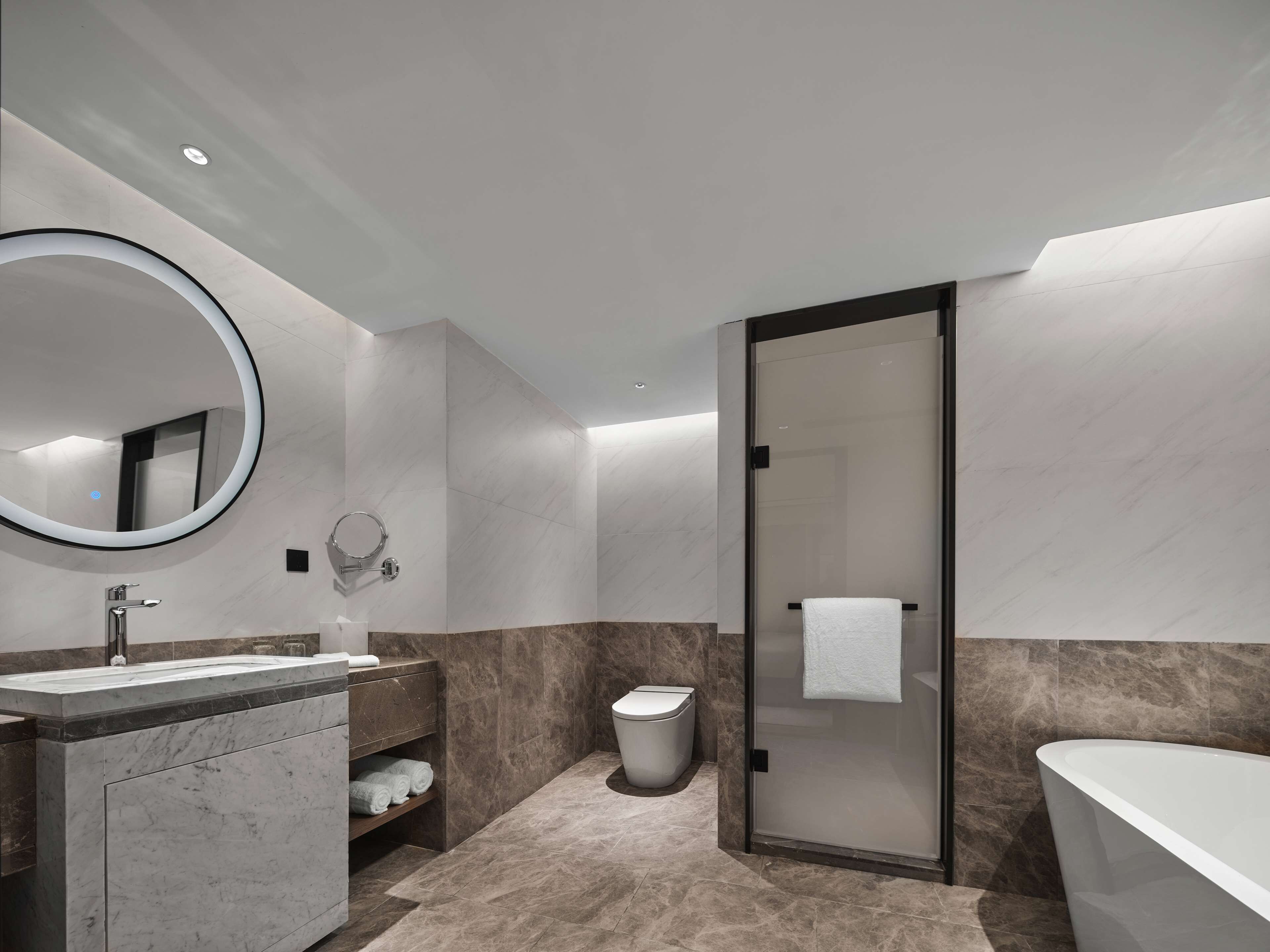 A modern bathroom with a large mirror, a sink, a toilet, and a glass-enclosed shower.