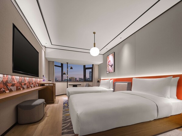 Una habitación de hotel moderna con un televisor de pantalla plana grande, dos camas con ropa de cama blanca, vistas a la ciudad a través de amplias ventanas y una pared con un diseño único.