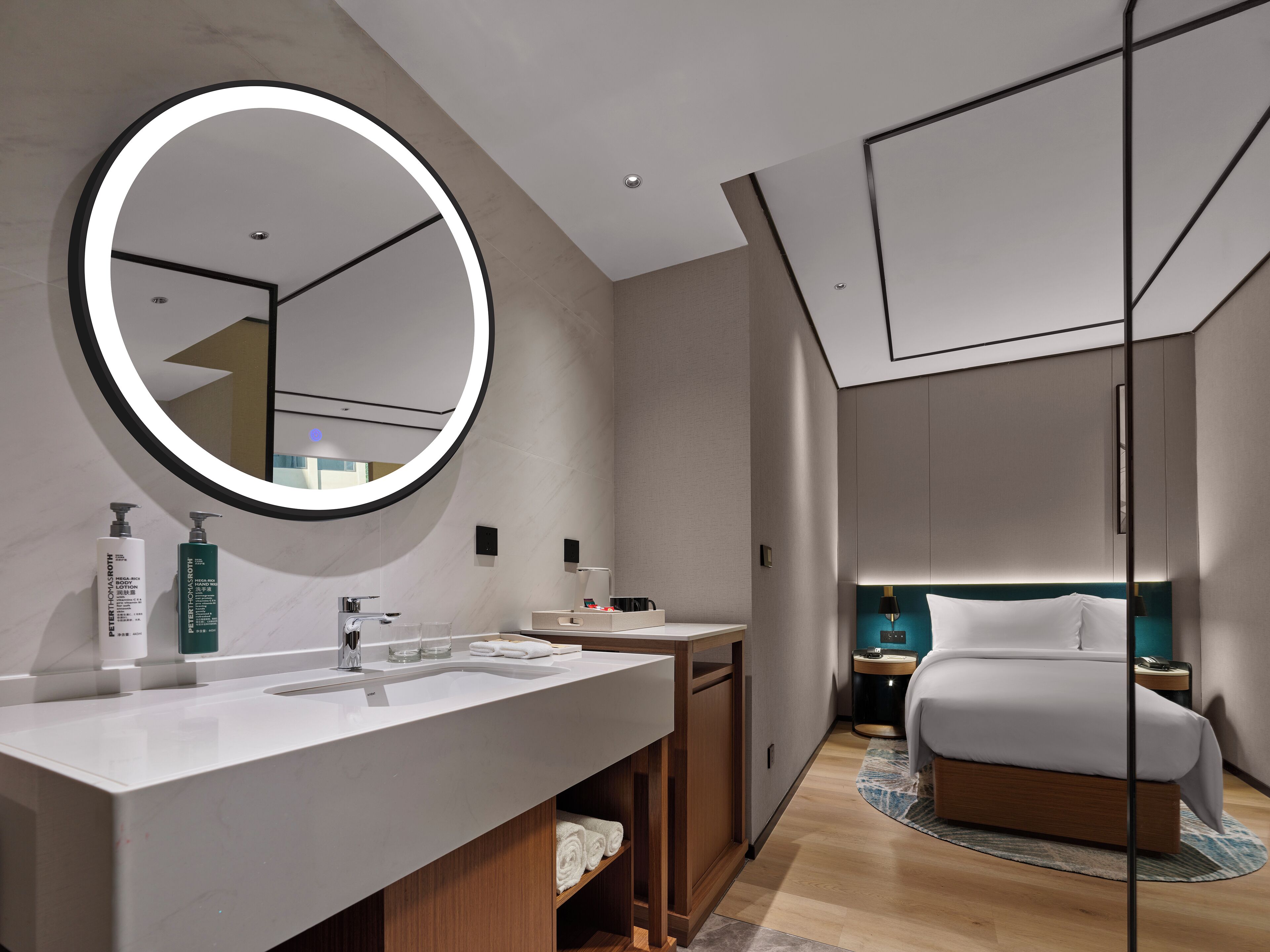 A modern hotel bathroom with a large mirror, a vanity with a sink, and toiletries.