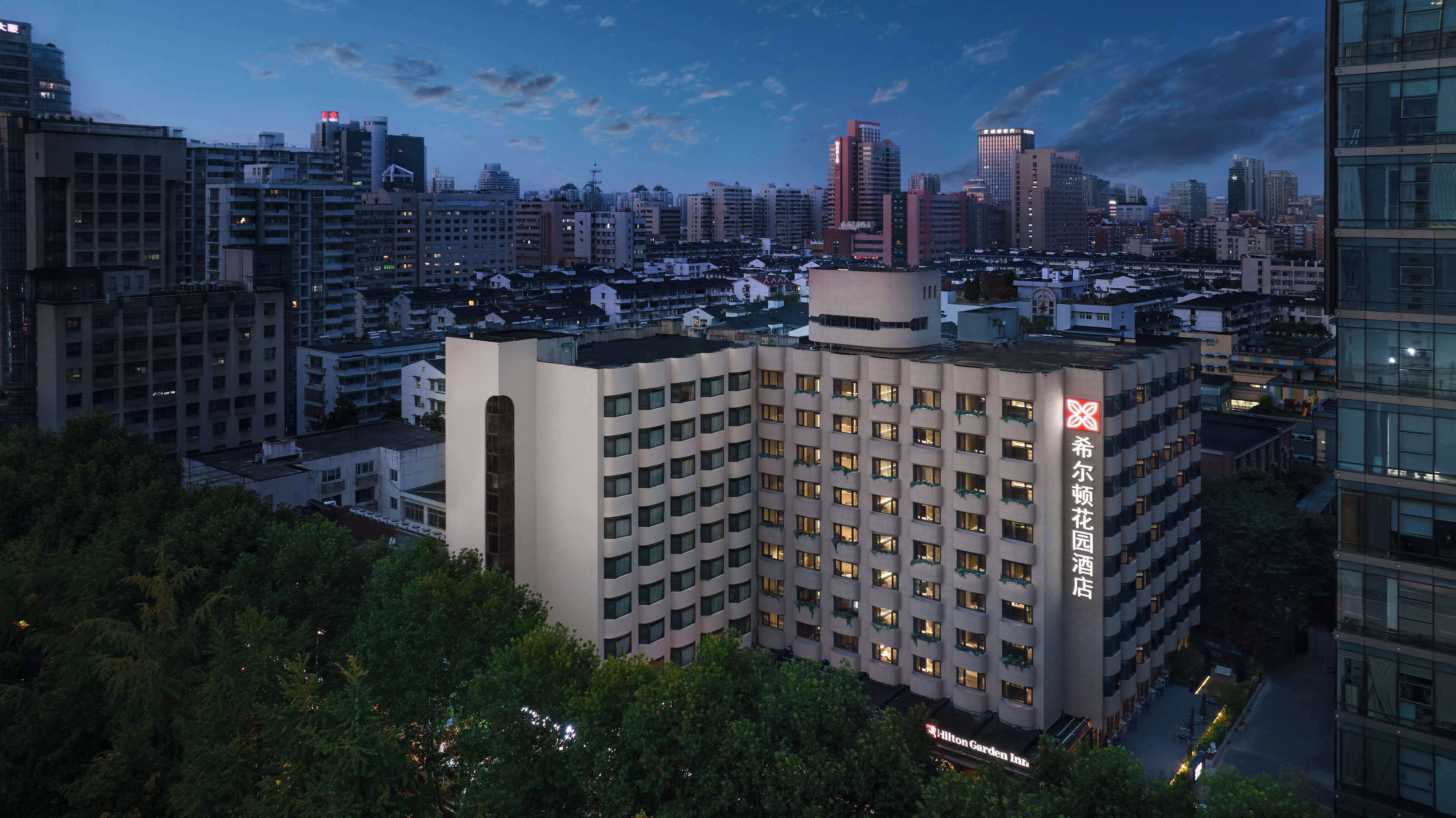 Un hôtel au design moderne, avec plusieurs étages et un logo rouge bien visible sur le côté.