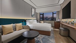 Una habitación de hotel moderna con cama, sofá y escritorio.