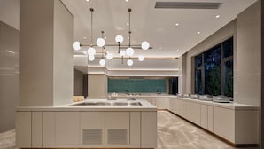 Una cocina moderna con una isla central, iluminación colgante y vistas al exterior a través de amplios ventanales.