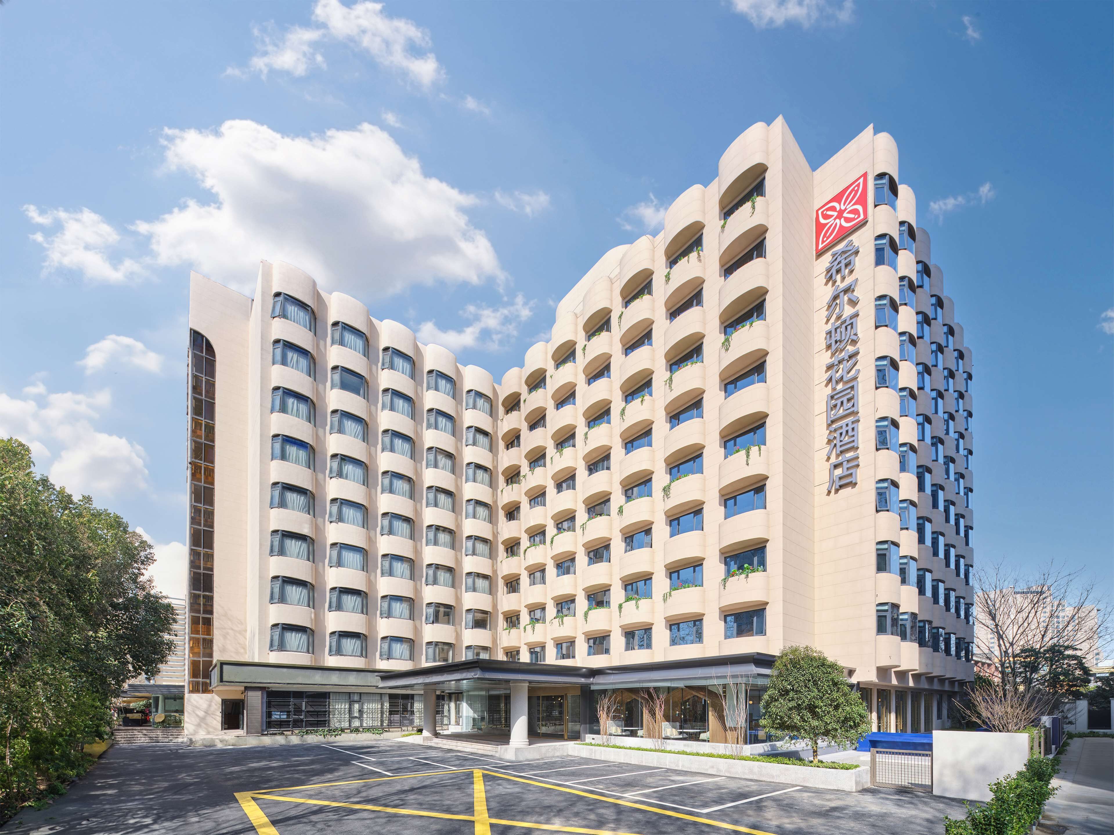 Un hôtel à plusieurs étages doté d’une architecture moderne, avec un logo bien visible sur sa façade.