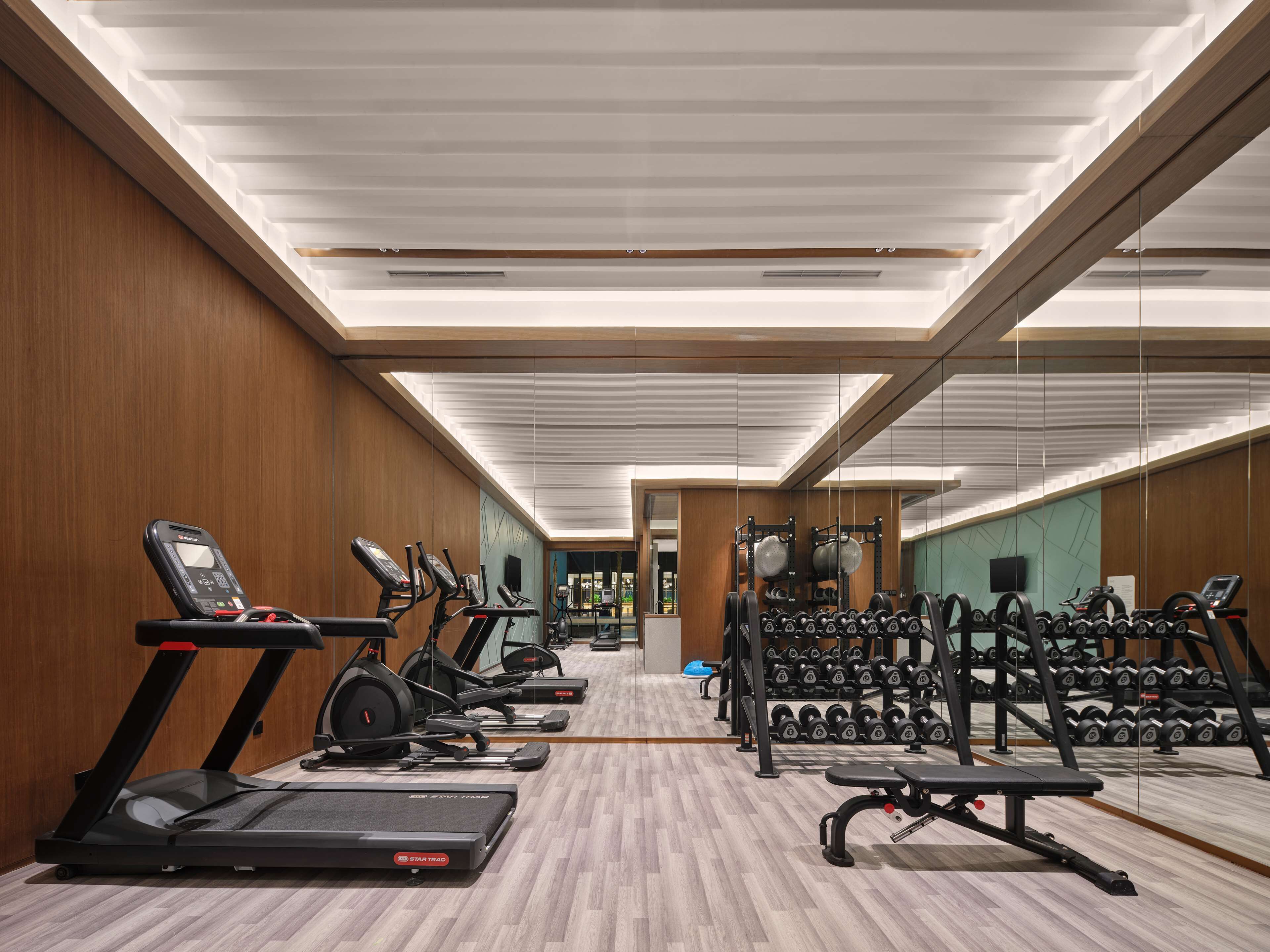 Een moderne sportschool met loopbanden, elliptische trainers en losse gewichten.