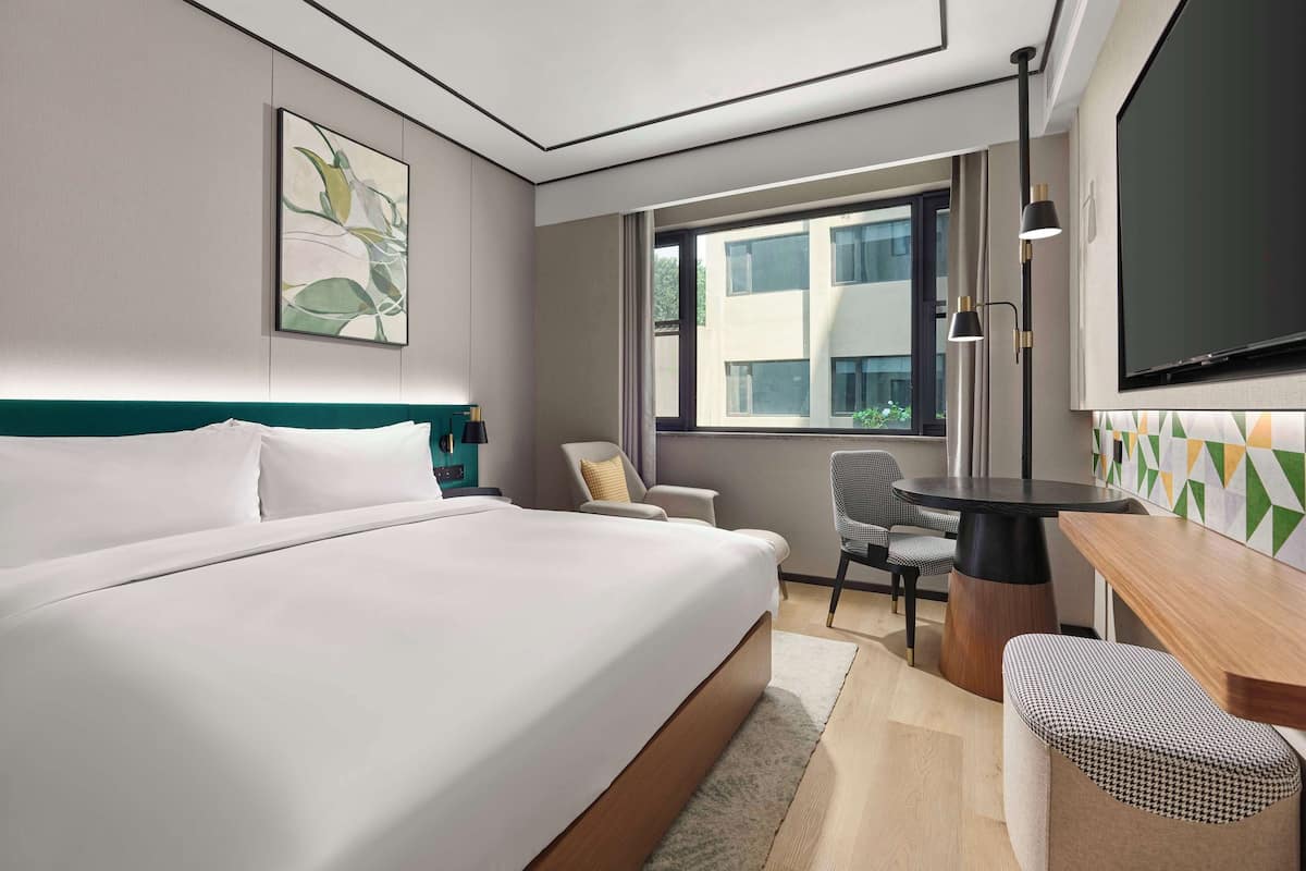 Una habitación de hotel moderna con una cama grande, un escritorio, una silla y un televisor.