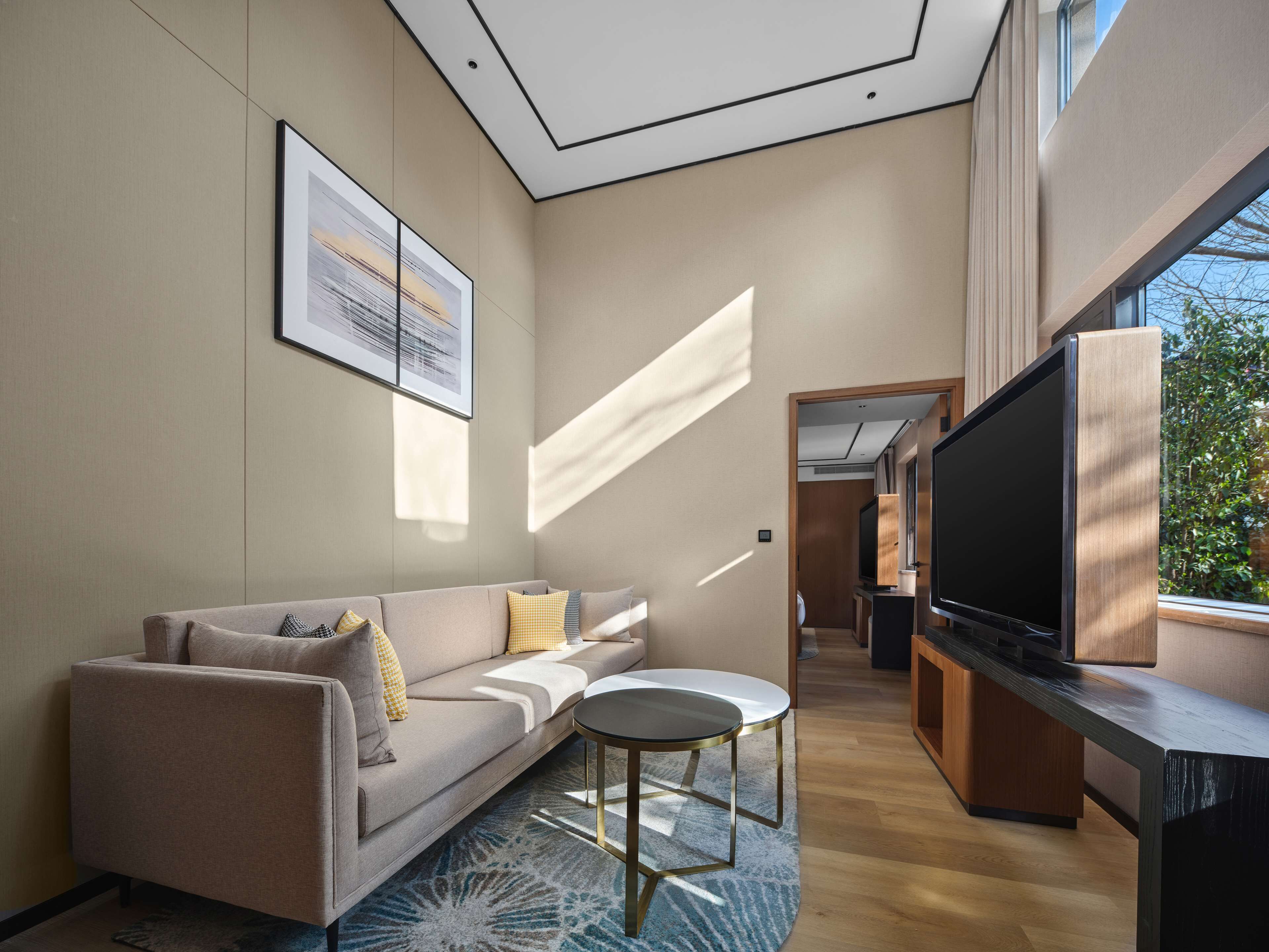 A modern living room with a sofa, a small round table, and a TV.