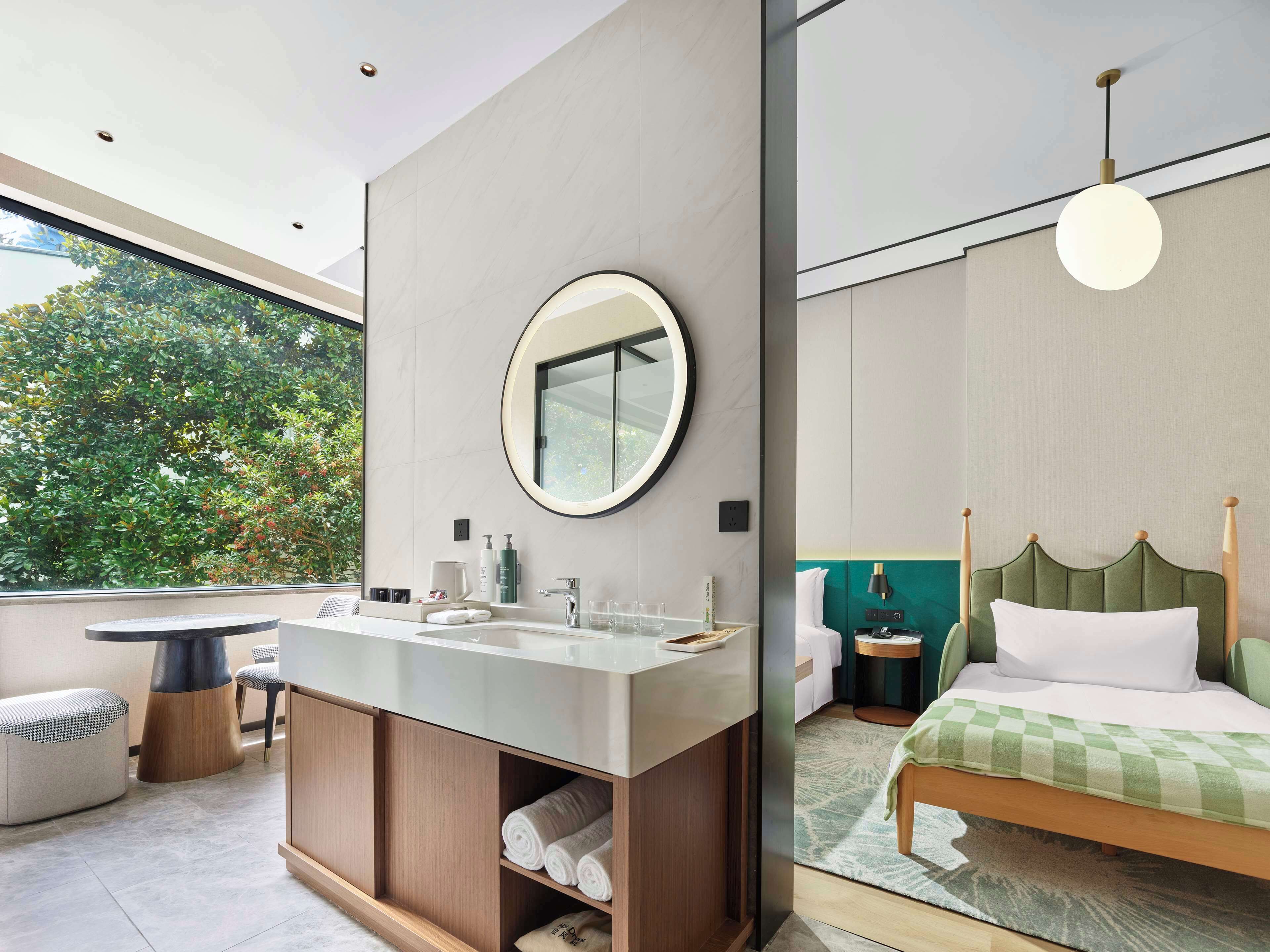 Un baño moderno con un espejo grande, un lavamanos y una ventana que ofrece vistas a la vegetación.