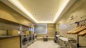 A modern laundry room with built-in washers and dryers, wooden cabinets, and a window providing natural light. - Atour Hotel Binjiang Binwen Road Hangzhou (Hangzhou)