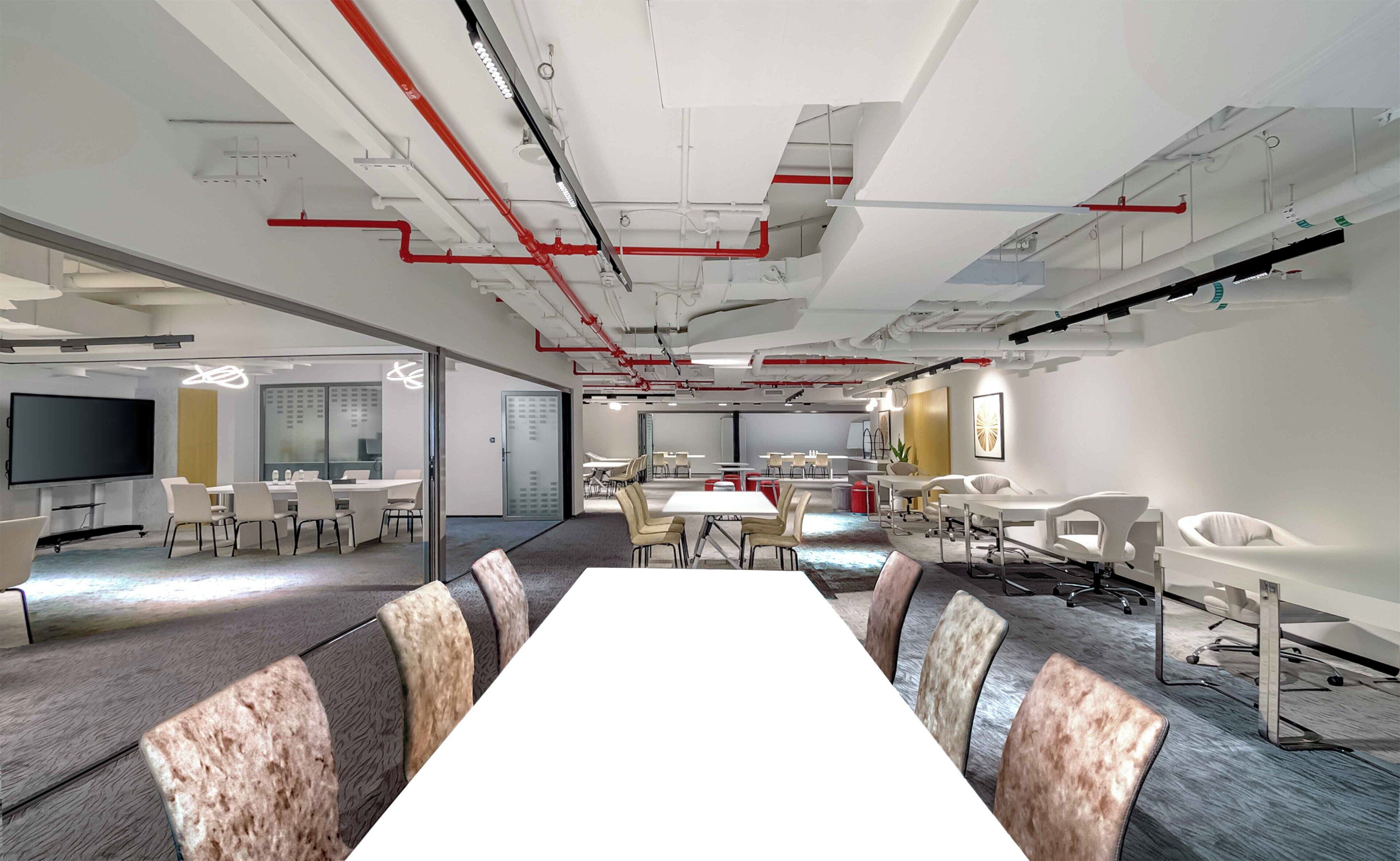 A modern conference room with a long table, multiple chairs, and a large screen.