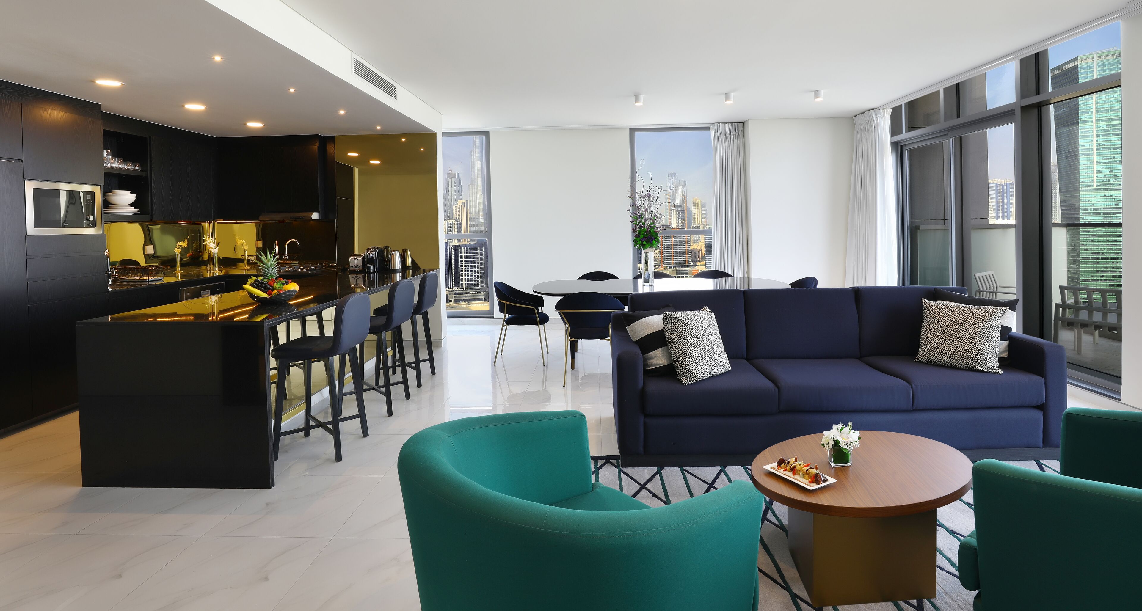 Een moderne woonkamer met een bank, stoelen, een eettafel en een keukenhoek.
