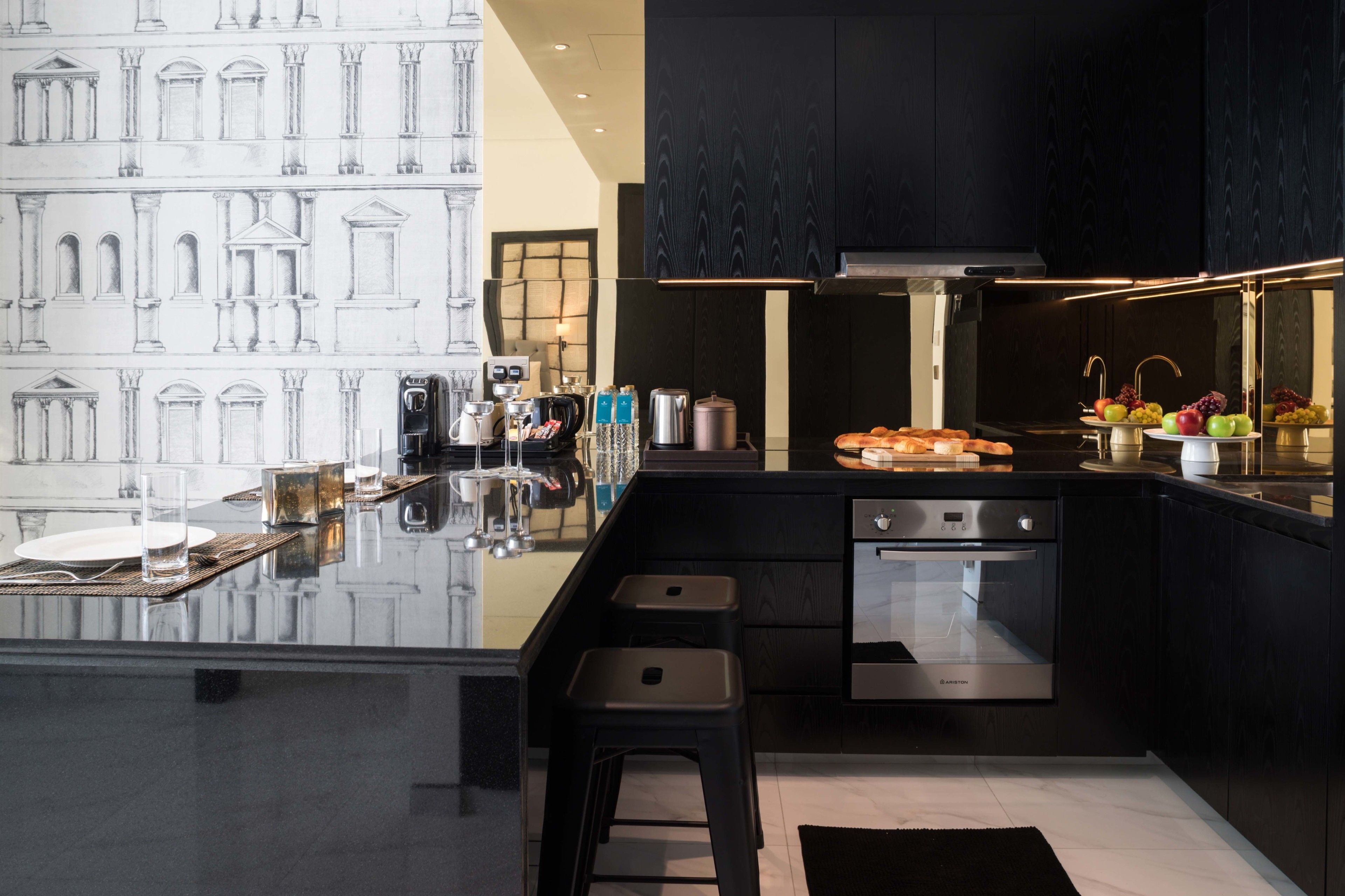 Una cocina moderna con una isla central, armarios negros, electrodomésticos de acero inoxidable y encimera de mármol.