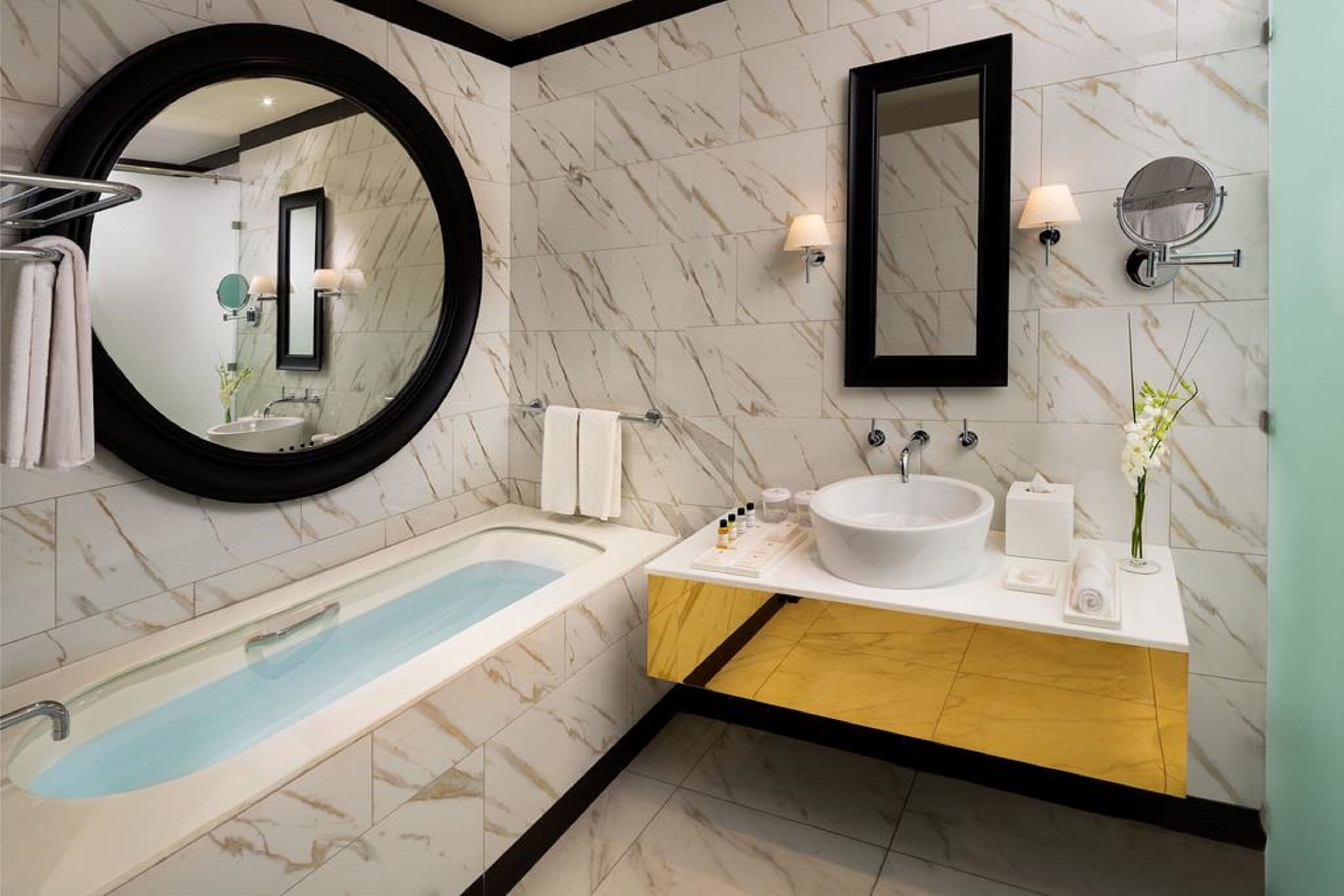Un baño moderno con una bañera independiente, un espejo grande y un lavamanos con lavabo y espejo.