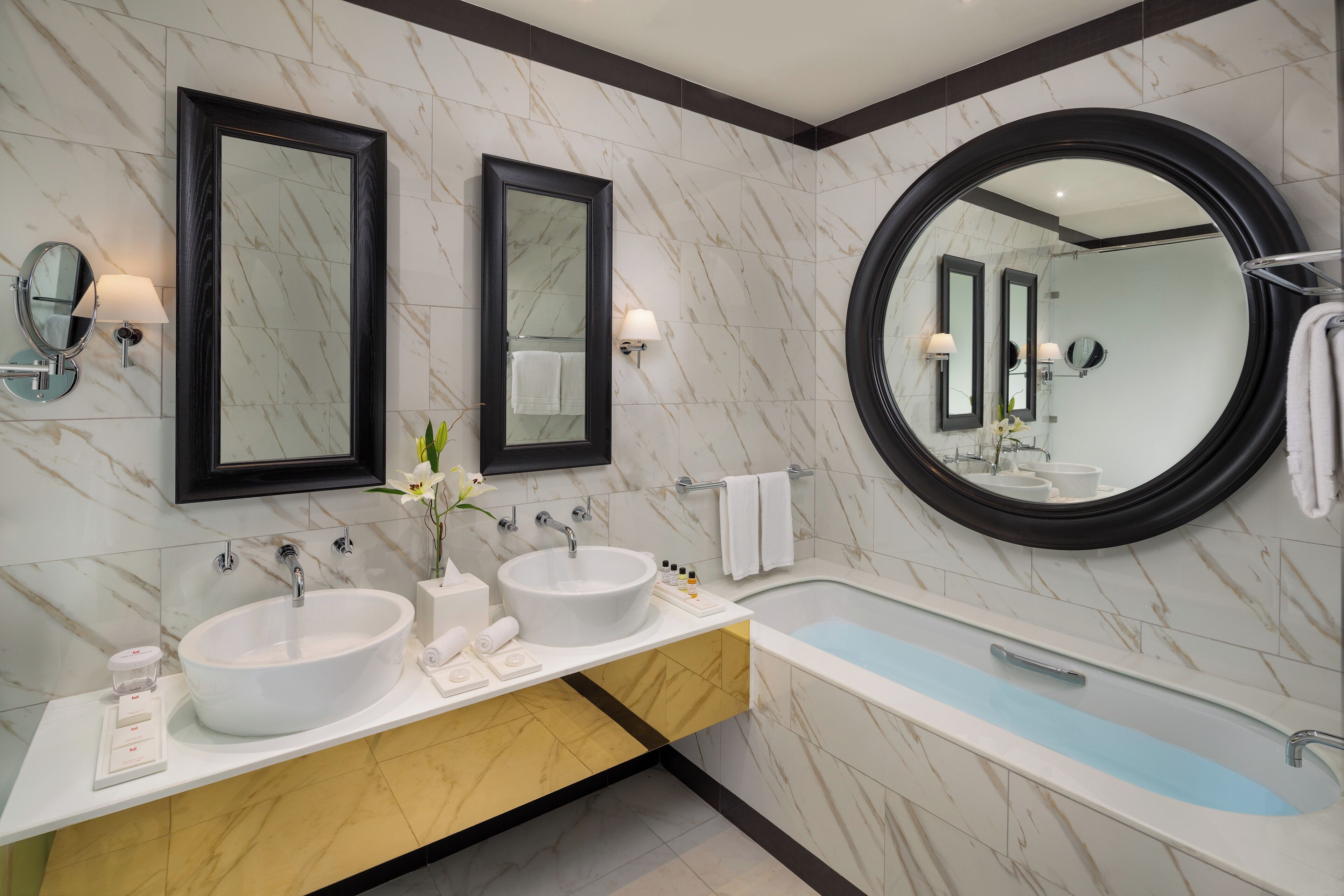 A modern bathroom with two sinks, a large bathtub, and two wall mirrors.
