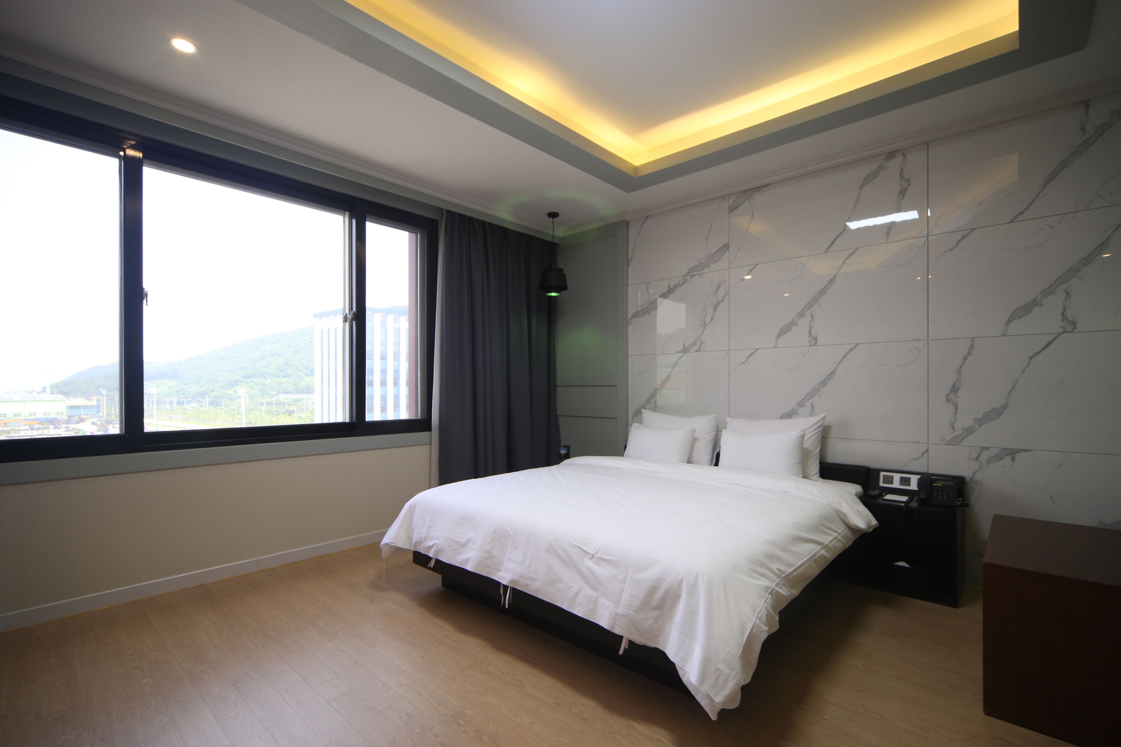 Une chambre d’hôtel moderne dotée d’un grand lit, d’une table de chevet, d’un bureau et offrant une vue sur la ville.