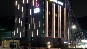 Een modern hotel met een opvallend 'B' logo, verticale lichtstroken en een brugstructuur op de achtergrond.