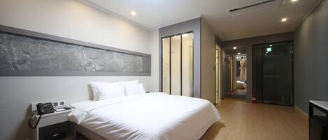 Una habitación de hotel moderna con una cama grande, teléfono en la mesita de noche y un vestidor.