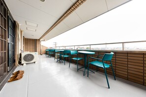Un vaste espace extérieur aménagé avec de nombreuses tables et chaises, un grand appareil de climatisation et une vue sur le paysage urbain.
