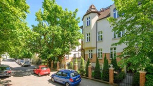 En bostadsgata med träd längs sidorna och parkerade bilar.