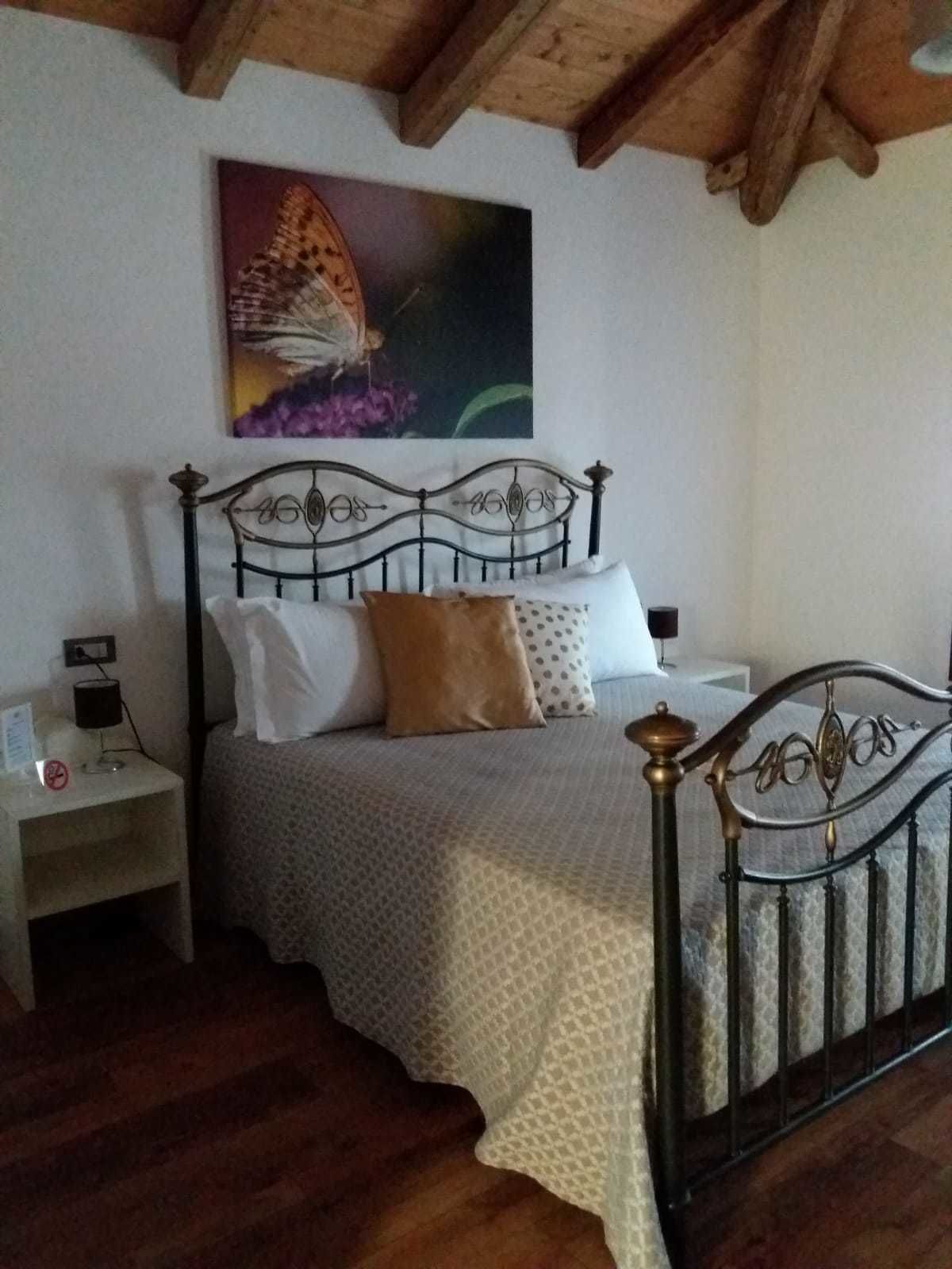 Un dormitorio con una cama, una mesita de noche y un cuadro de una mariposa en la pared.
