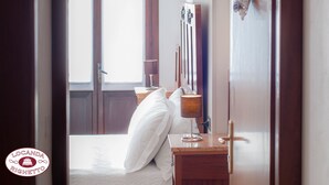 A hotel room with a bed, a bedside table with a lamp, a window, and a wall-mounted decoration. - Locanda Righetto (Quinto di Treviso)