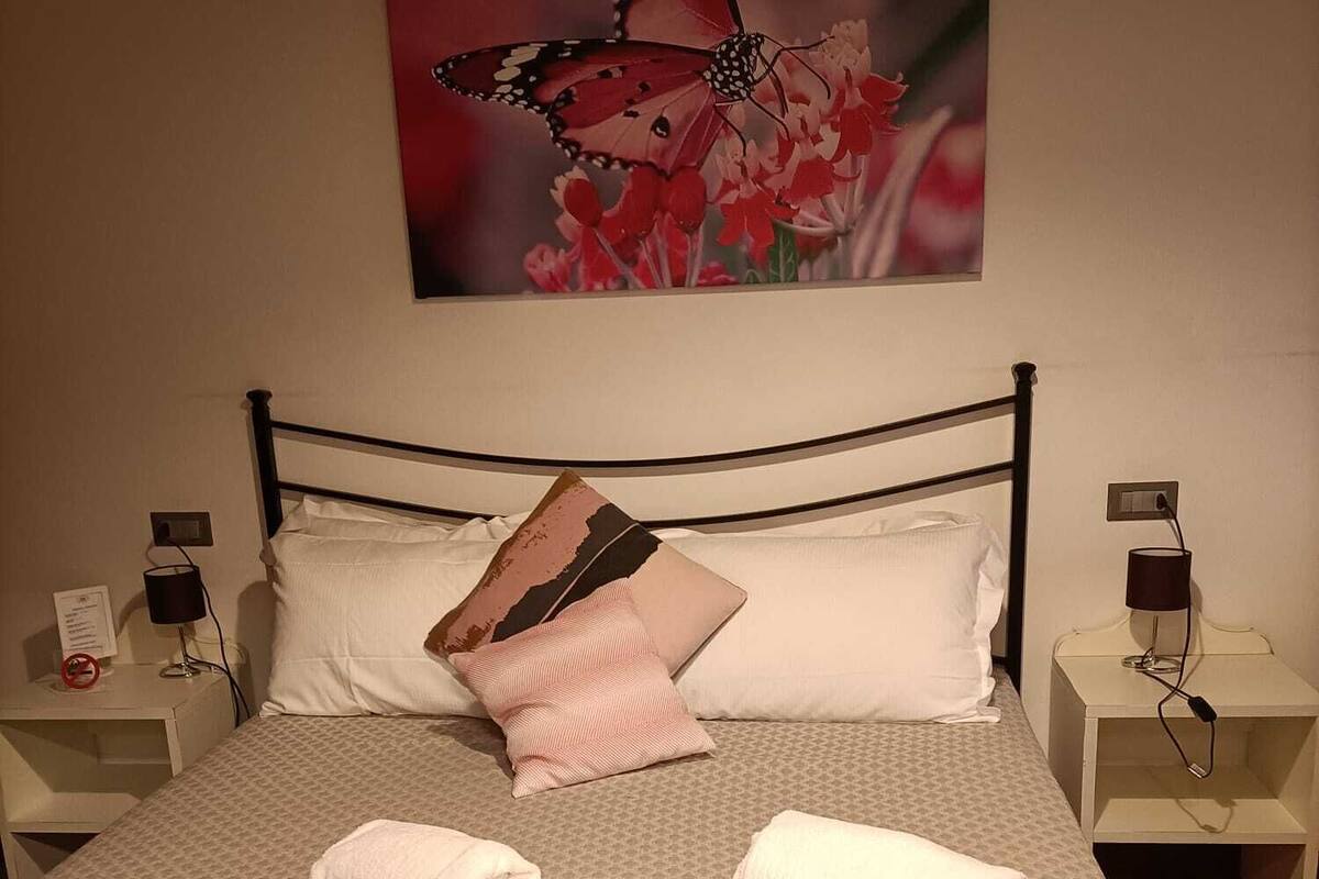 A neatly made bed with a patterned bedspread, two pillows, and two rolled towels.