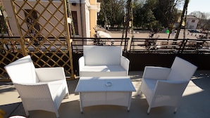 A patio with white wicker furniture, including chairs and a table, and a decorative fence. - Locanda Righetto (Quinto di Treviso)
