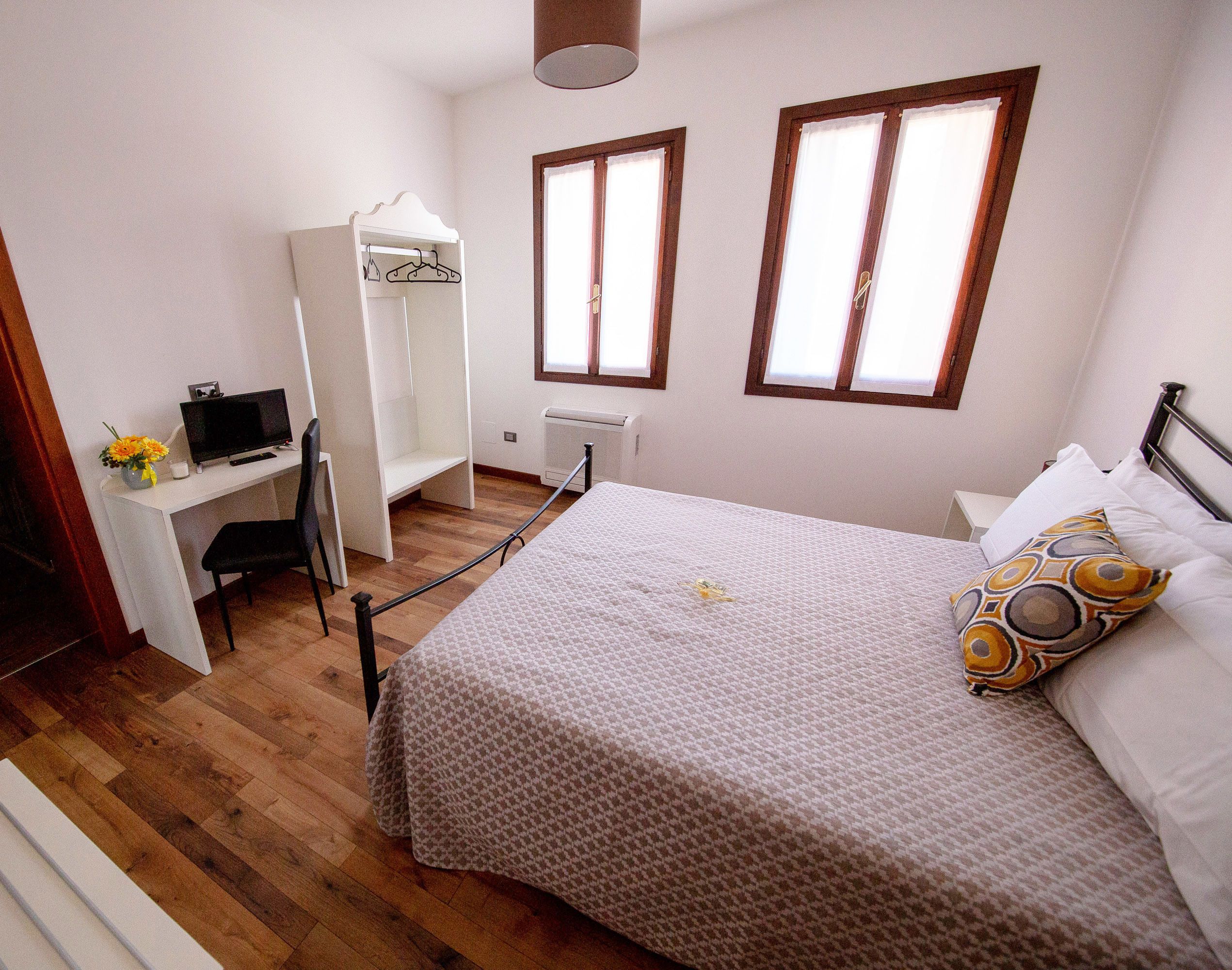 Un dormitorio con una cama, un escritorio con computadora, una silla y un armario.