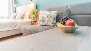 A modern living room with a grey sofa, a white armchair, and a small table with a bowl of fruit. - Apartament Przytulny –2 sypialnie w centrum Starówki Gdańskiej (Gdansk)