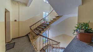 A multi-level interior with a wooden staircase, a potted plant, and a window providing natural light. - Apartament Przytulny –2 sypialnie w centrum Starówki Gdańskiej (Gdansk)