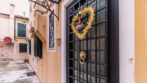 A building with a black metal gate, a golden wreath, and a lion head knocker. - Corderie de la Tana Biennale Exhibition (Venice)