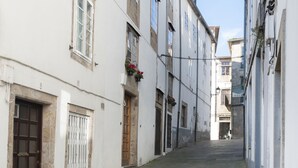 A narrow street with white buildings, stone paving, and a clear sky. - Los truques (Santiago de Compostela)