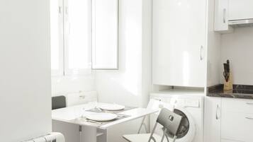 A modern kitchen with a built-in washing machine, a dining table with chairs, and a radiator.