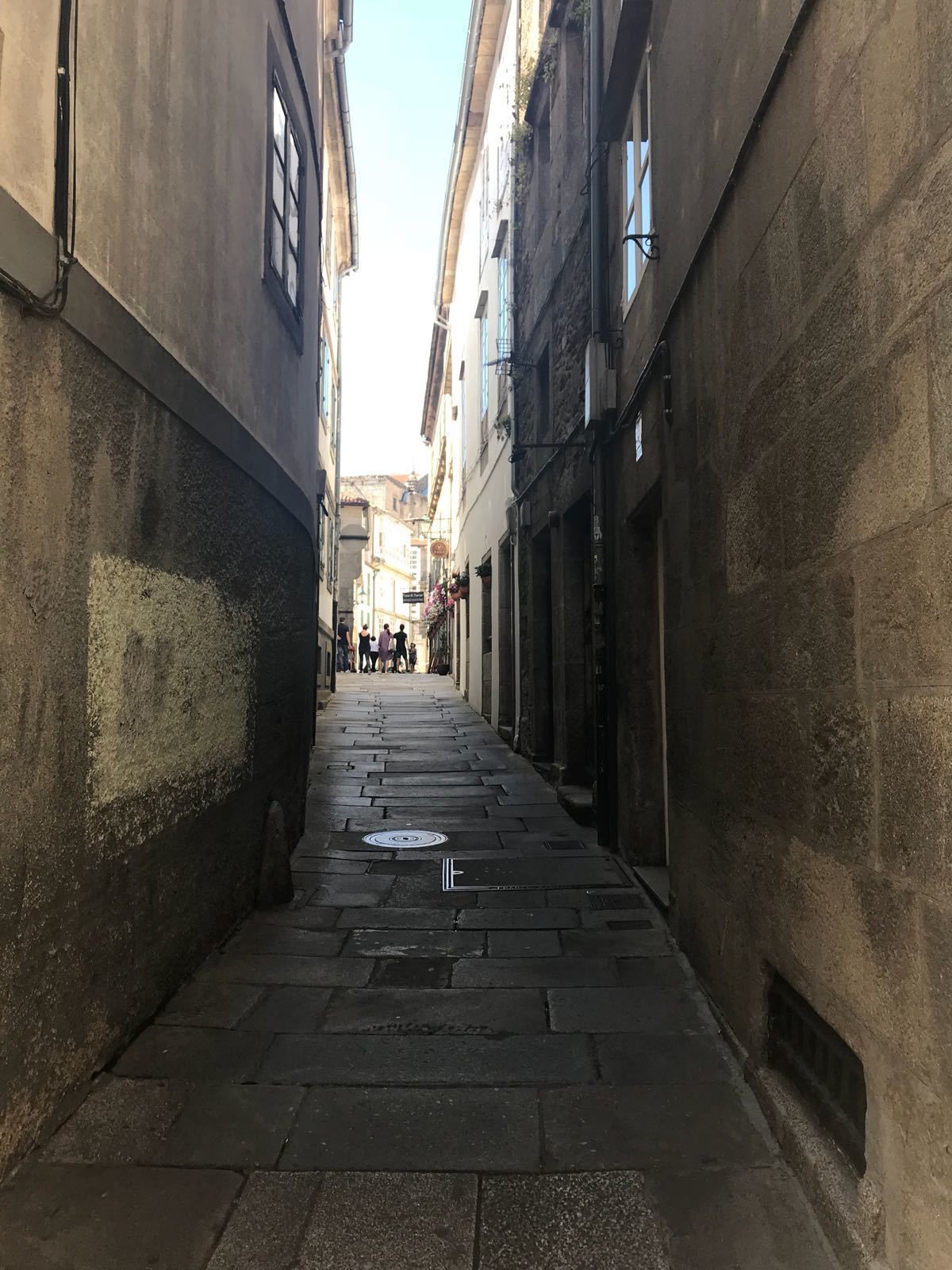 Un estrecho callejón empedrado, flanqueado por edificios con ventanas y puertas.